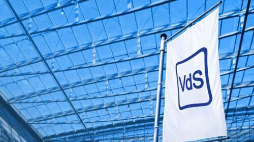 Fahne der VdS Schadenverhütung vor blauem Hintergrund mit Gebäudestruktur