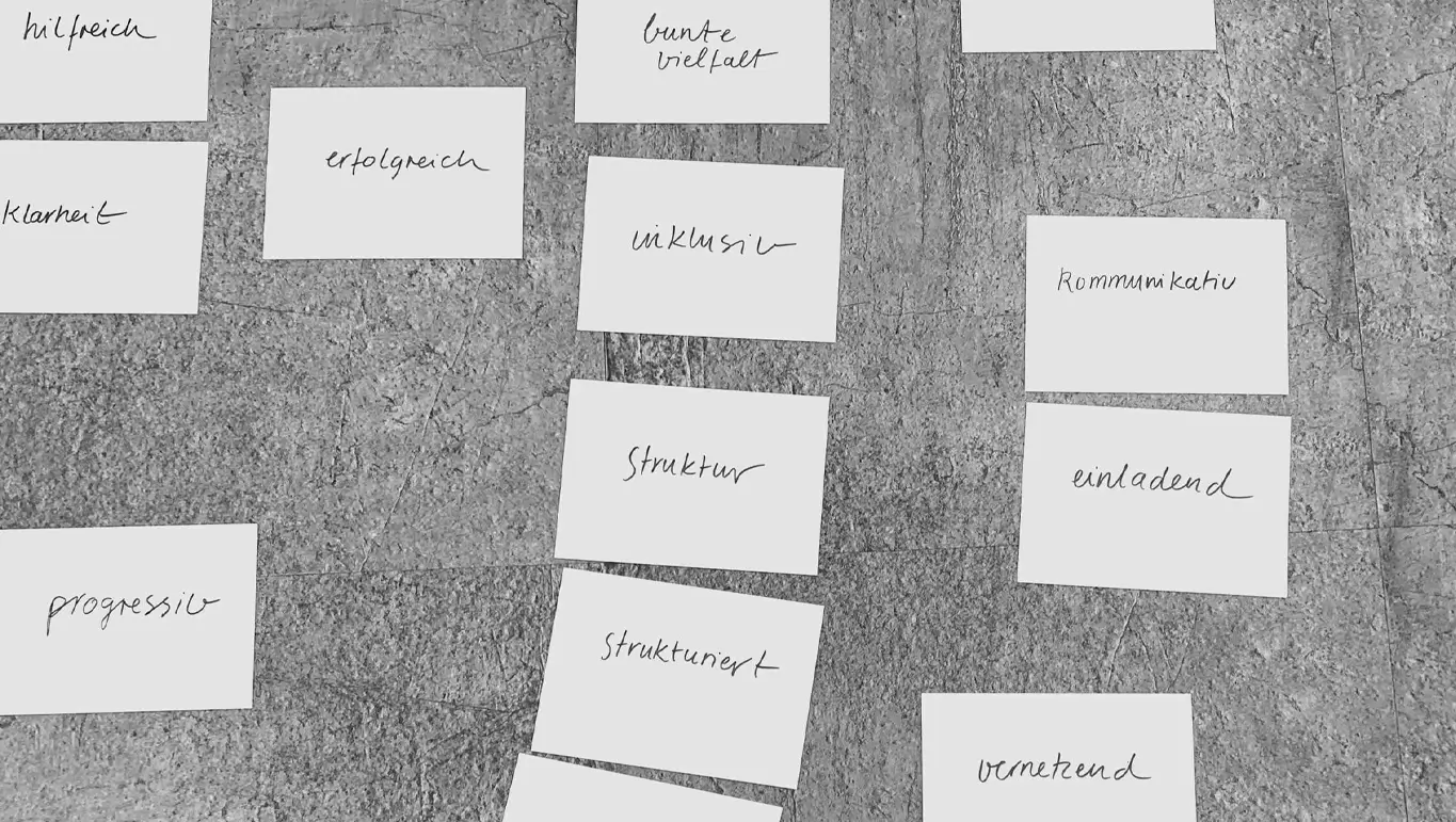 Handschriftliche Ergebniskarten aus einem Markenworkshop bei AWO Mittelrhein, auf grauem Steinboden ausgelegt — Begriffe wie „Struktur", „inklusiv", „erfolgreich" und „vernetzend" clustern die gemeinsam erarbeiteten Markenwerte der Verbundstruktur.