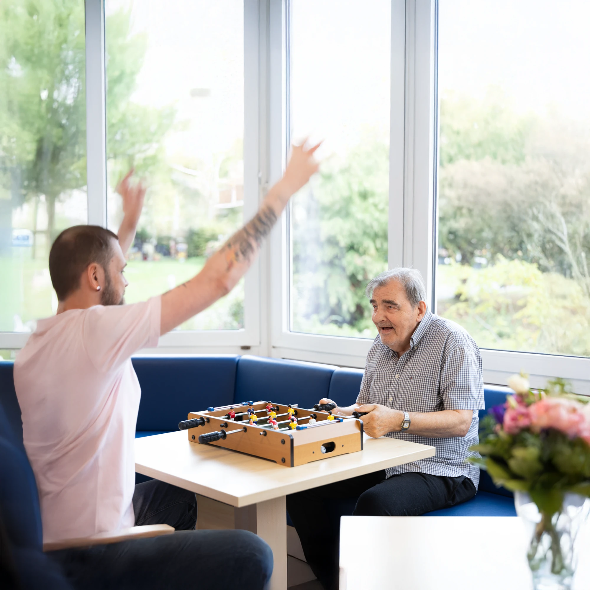 Bewohner und Pfleger beim Tischkickern in einer Einrichtung der AWO GESA